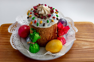  Easter cake and colored eggs in a plate on a wooden background. Orthodox Easter.