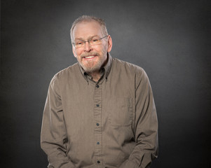 Fototapeta premium Smiling balding relaxed handsome older mature man with beard and glasses
