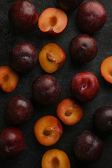Plums. Fresh plum. Whole and halves of blue ripe plums on a dark textured background. Natural fruit background. Harvest. Autumn harvest. Blue plums. Close-up.