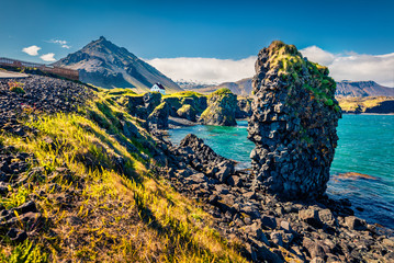 Amazingly shaped basalt columns on the shores of Atlantic Ocean. Sunny summer view of small fishing...