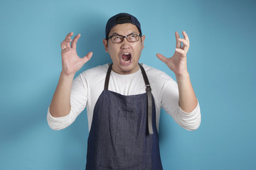 Naklejka premium Portrait of Asian male chef or waiter screaming loud, stress tired of work