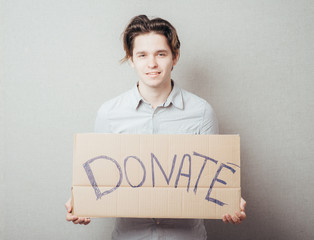 a man with an inscription on cardboard donate