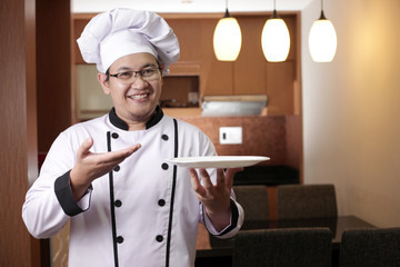 Asian Male Chef Shows Empty White Plate, Presenting Something, Copy Space