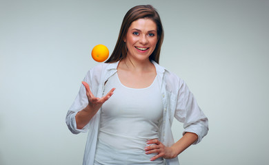 Smiling woman throws up orange fruit.