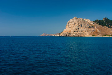 Fototapeta na wymiar Large stone cliff on the shore of the blue sea