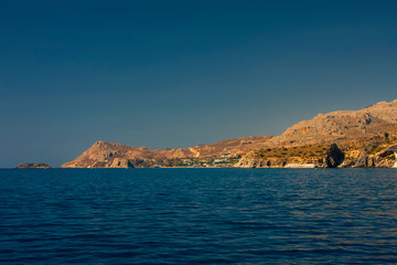 Obraz premium The blue sea goes into the distance to the rocky shore