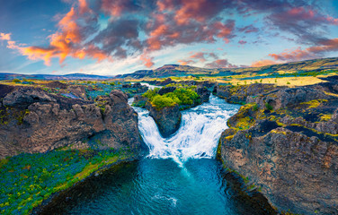 View from flying drone. Dramatic sunset on Hjalparfoss Waterfall. Splendid summer scene of Iceland, Europe. Beauty of nature concept background.
