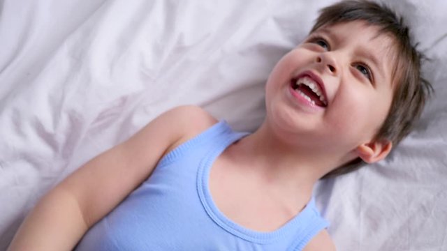 mom tickles her little son lying on the bed