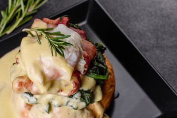 Eggs benedict or eggs florentine on a black plate in the cafe