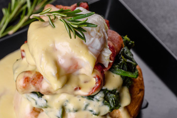 Eggs benedict or eggs florentine on a black plate in the cafe