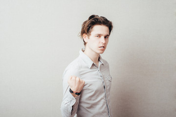 Closeup portrait, hostile angry irritated upset young man raising shaking fists at you to camera...