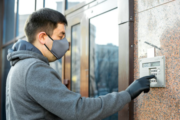 Courier delivers the parcel to the door, rings the intercom. Men in latex gloves and medical mask contactless delivers a package to the client during the quarantine period.