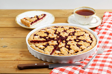 Homemade cherry pie crostata and cup of tea on wooden table. Shallow focus.