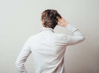 young man from the back scratching his head