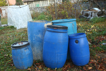The blue plastic barrels for storage of chemicals . Stockpile of used blue plastic drums for storing water and other liquids.