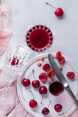 Ripe berries of a cherry and a glass of sherry on a white background.