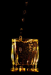 Splashes and drops of water in a glass are isolated on a black background.