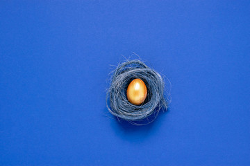 Happy easter concept. Festive spring arrangement of a golden painted egg nest on a fashionable minimalistic background. - obrazy, fototapety, plakaty