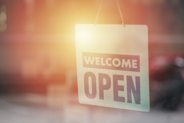 Open and welcome sign broad through the glass of window