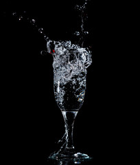 Splashes and drops of water in a glass are isolated on a black .