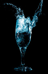 Splashes and drops of water in a glass are isolated on a black background.
