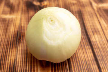 Fresh peeled onions on a wooden background.