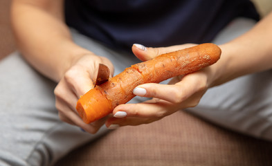 Girl peeling boiled carrots with a knife.