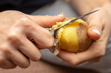 Girl peeling boiled potatoes with a knife