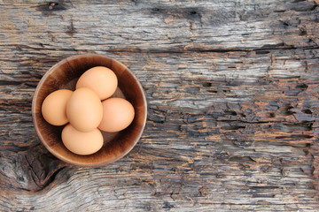 Fresh brown eggs in wooden bowl on wooden background. Top view. Rural still life, natural organic healthy food concept. Copy space.