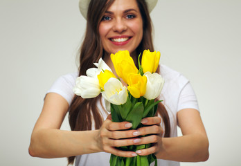 Smiling woman holding tulip flowers in front of face.