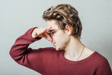 The man closed his nose on the stinky smell. On a gray background.