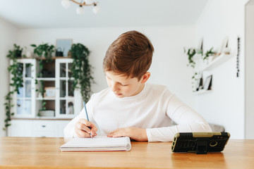 Healthy child writing with pen, staying at home. Homeschooling concept