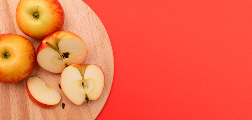  Whole and cut into pieces apples lie on a round cutting board on a red background.Harvest coronavirus concept.The concept of food shortage due to the covid-19.Concept healthy food.Copy space