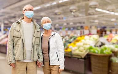 health, quarantine and pandemic concept - senior couple wearing protective medical mask for protection from virus holding hands over supermarket on background