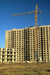 Fototapeta na wymiar An image of a tower crane against the background of a house under construction.