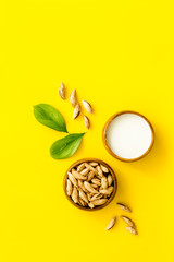 Alternative milk made from almond. Drink near unpeeled on yellow table top-down copy space