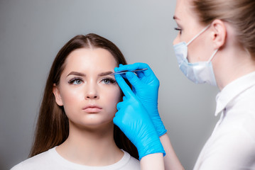 Permanent makeup. Permanent tattooing of eyebrows. Cosmetologist applying permanent make up on...