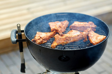 cooking, culinary and food concept - close up of barbecue meat roasting on brazier grill outdoors