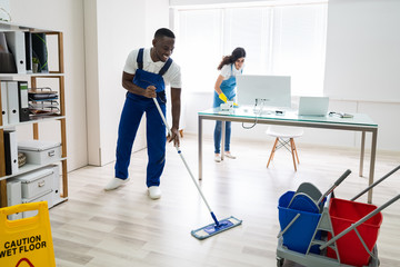 Male And Female Cleaners Cleaning Office