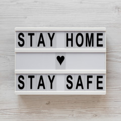 'Stay home stay safe' words on a lightbox on a white wooden surface, top view. Overhead, from...
