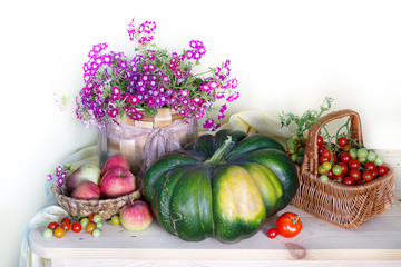 Still life with tomatoes and apples in a basket ,flowers in a vase.