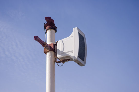 Outdoor speaker or tannoy on a rusty post on a blue sky
