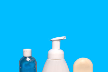 Blue background with a white bottle of liquid soap, a bottle with antibacterial hand gel and a white hand soap