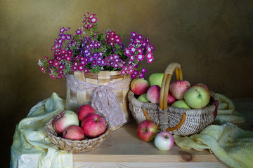 Still life with tomatoes and apples in a basket ,flowers in a vase.