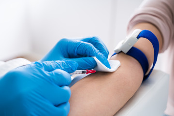 Doctor Injecting Patient With Syringe To Collect Blood