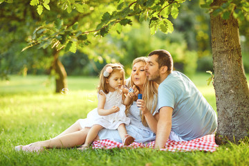 Fototapeta premium Happy family is hugging while sitting in the park.