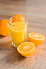 Oranges in peel and cut and juice-fresh on the wooden table of the house. Useful food, vitamins for health.
