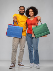 sale and people concept - happy african american couple with shopping bags over grey background