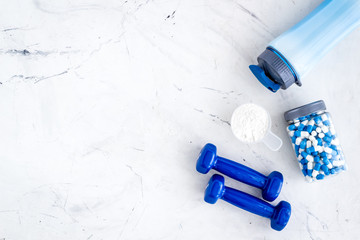 Creatine capsules, protein near shaker and dumbbells - sports supplements - flat lay on white background top view copy space