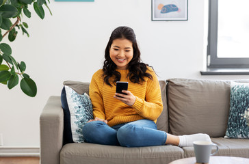 people, technology and leisure concept - happy smiling asian young woman in yellow sweater with...